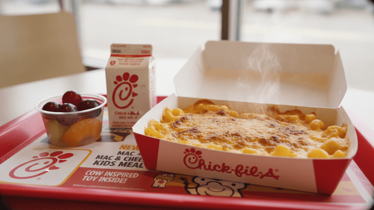 A Chick-fil-A Kids Meal on a red tray, featuring a steaming Mac & Cheese, a milk carton, and a fruit cup.