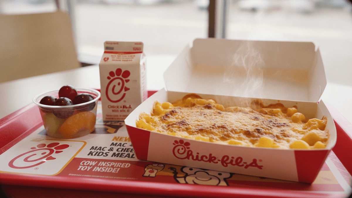 A Chick-fil-A Kids Meal on a red tray, featuring a steaming Mac & Cheese, a milk carton, and a fruit cup.