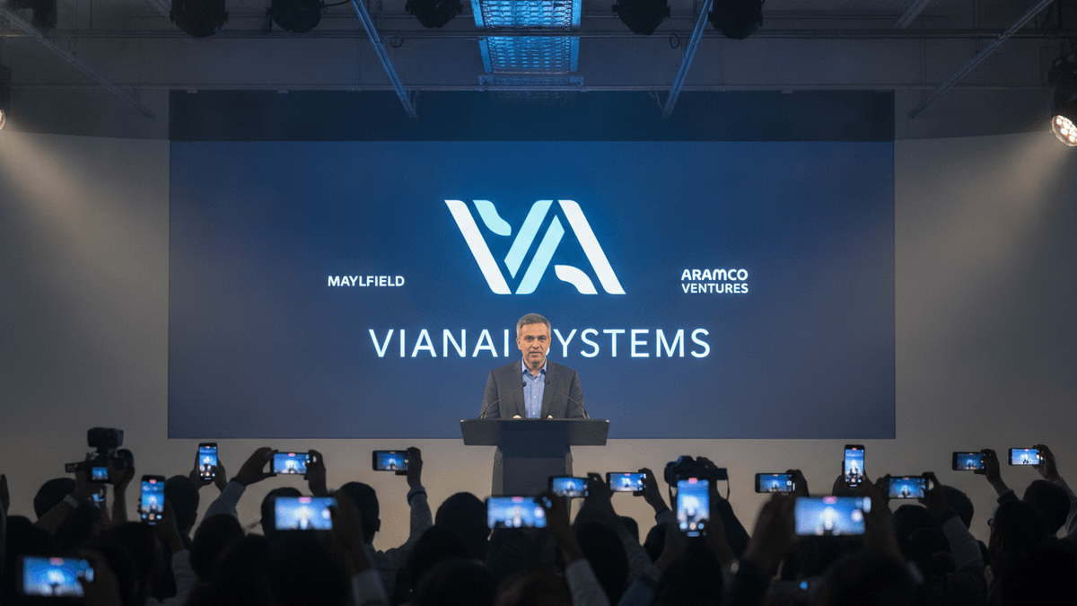 Vishal Sikka, framed by a wide-angle lens, stands behind a dark podium, addressing an audience. The audience holds up phones, recording the event. Behind Sikka is a large screen displaying "VianAI Systems," "Mayfield," and "Aramco Ventures."