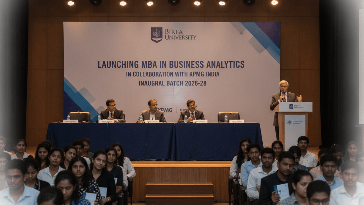 A university auditorium with a panel of speakers on stage and an audience of students seated in rows.