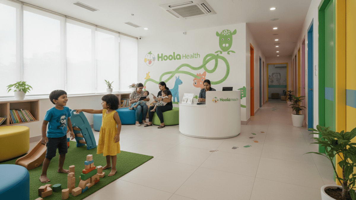 Wide shot of a brightly lit paediatric clinic reception with children playing and parents waiting.