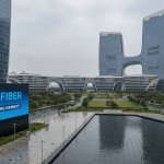 A large digital billboard displaying "Jio Fiber IPO FILING IMMINENT" stands before modern corporate buildings and a reflecting pool.
